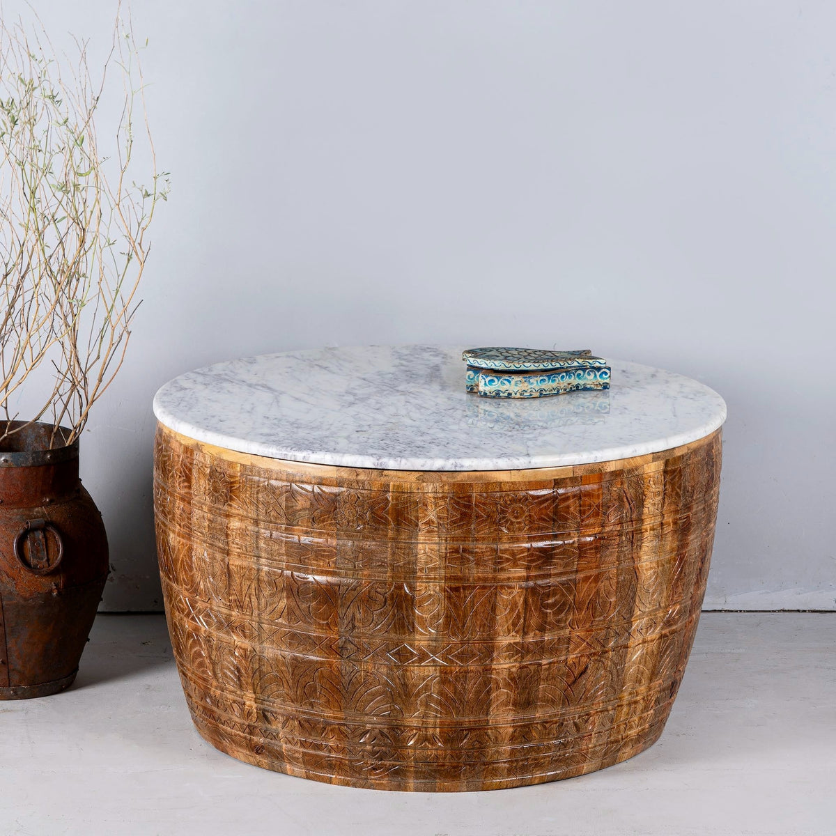 Round wooden table with marble top against a plain wall