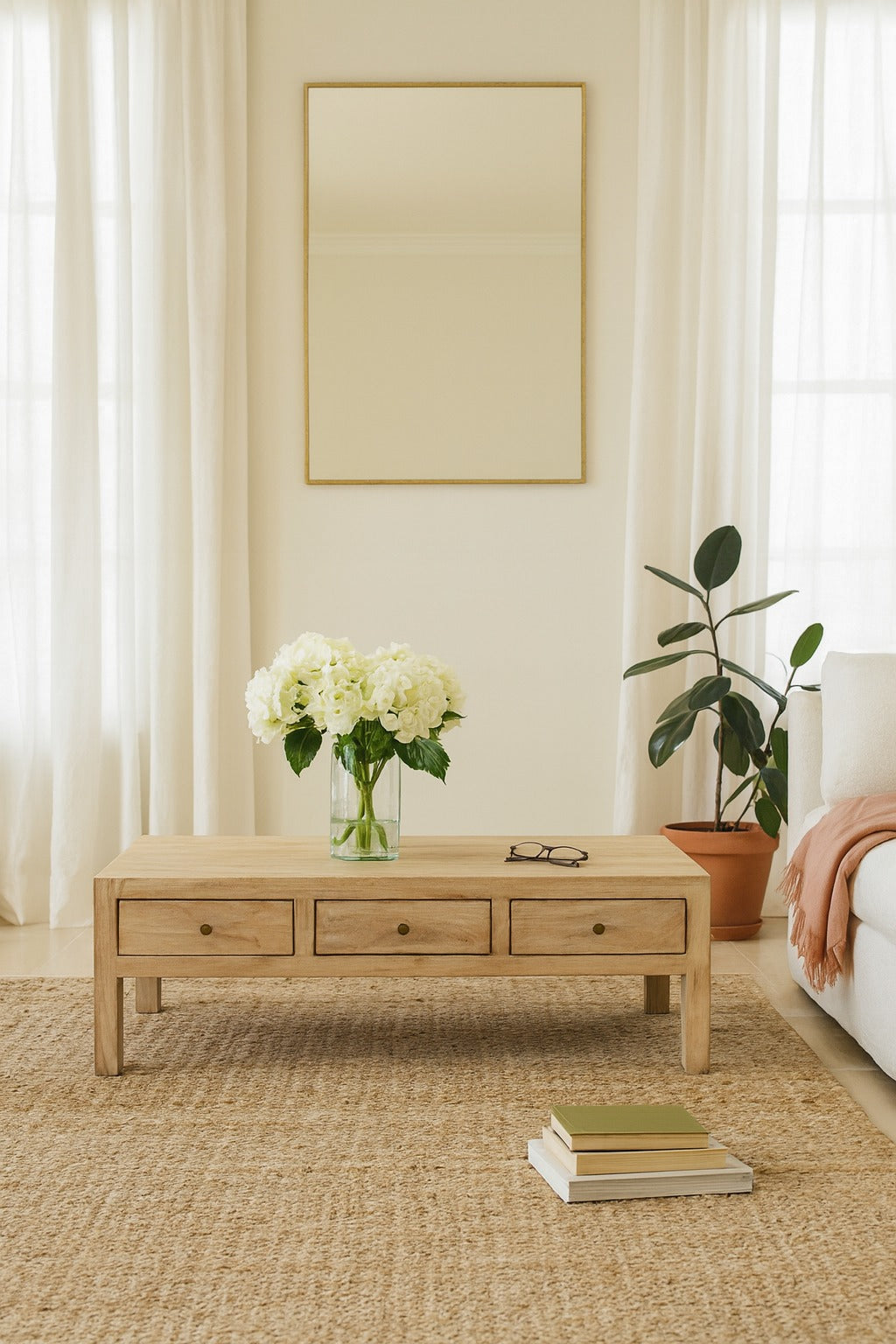 Living room with a wooden coffee table, flowers, books, and a plant.