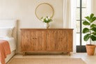 Wooden dresser in a bedroom with a mirror and plants