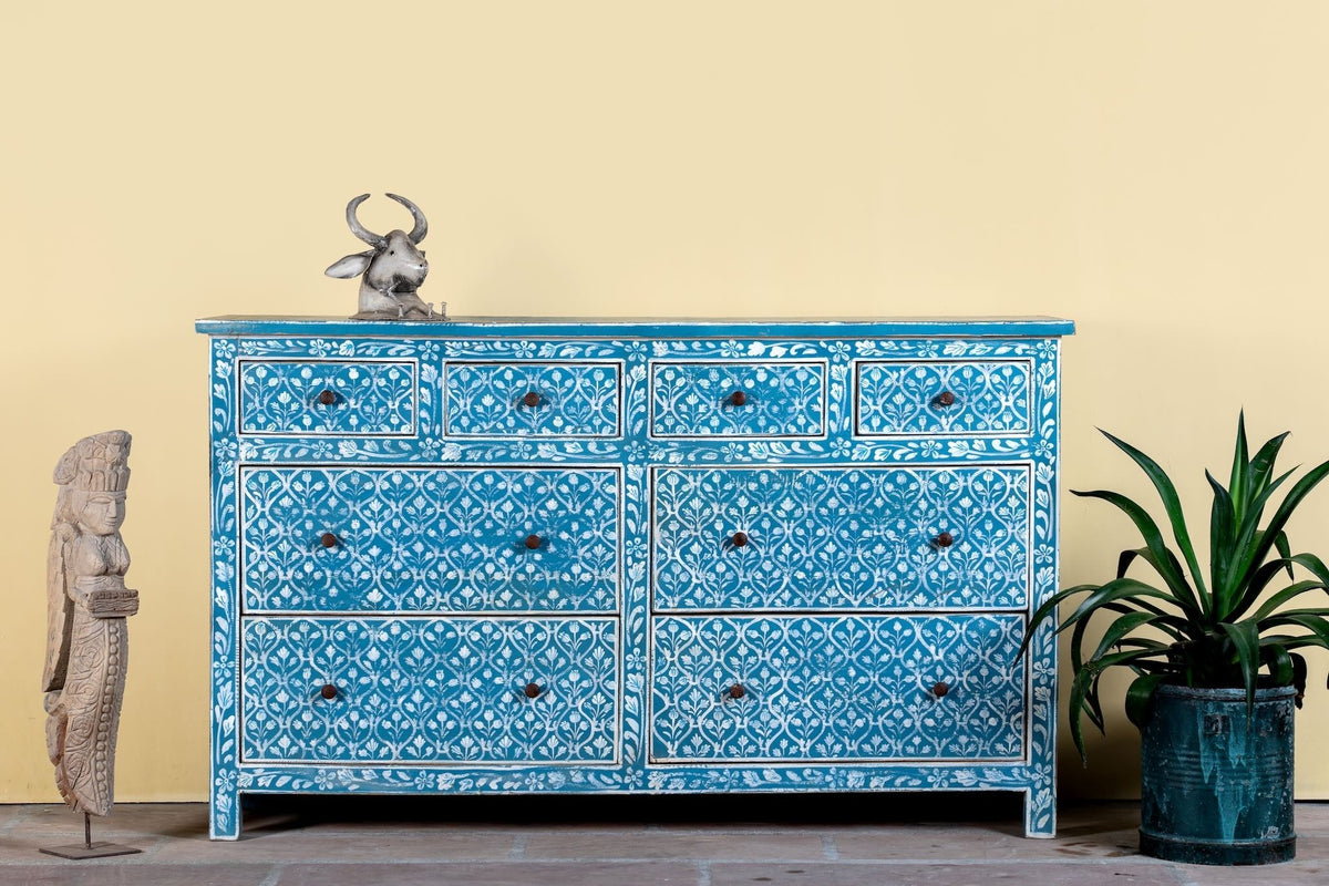 Blue dresser with intricate patterns against a yellow wall