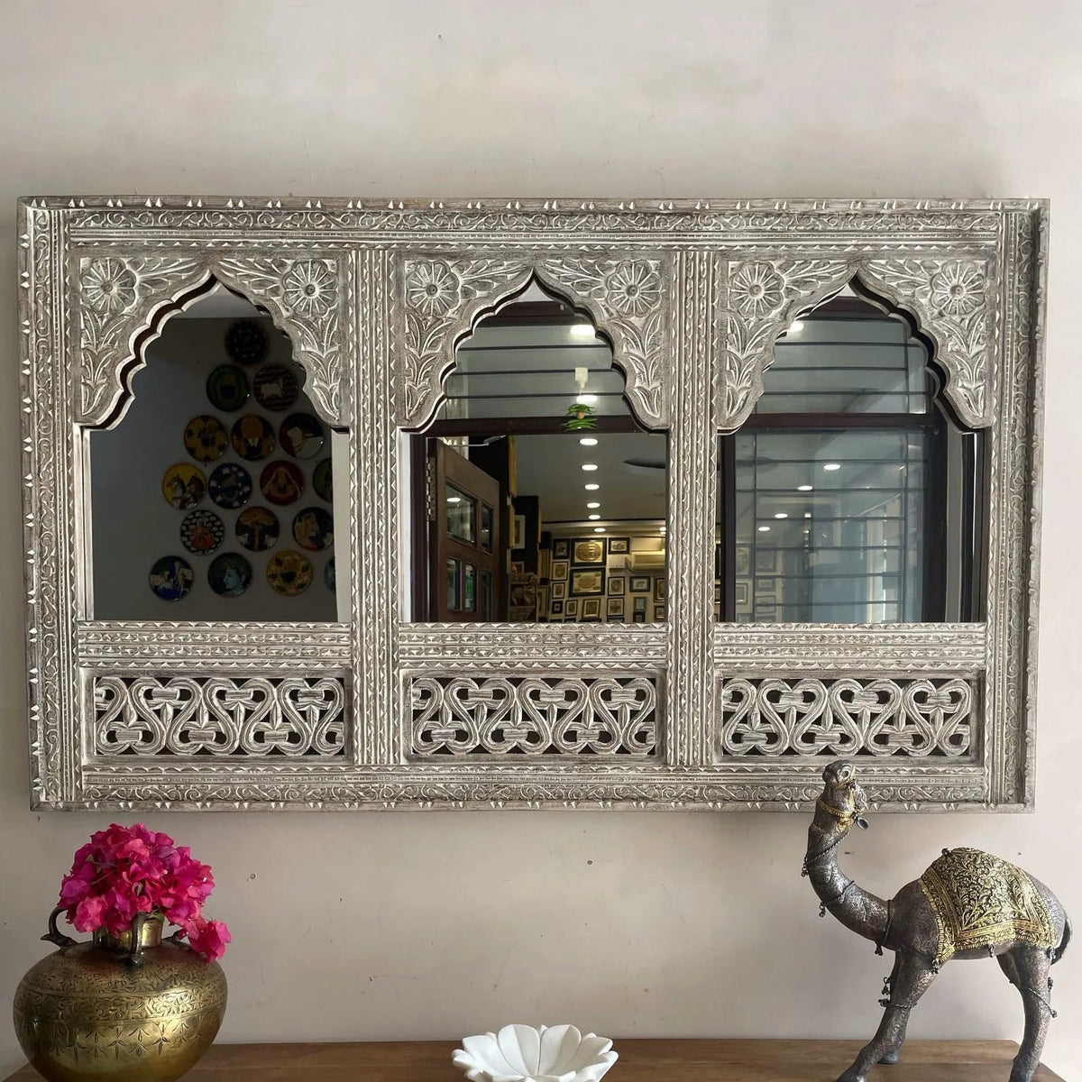 Decorative wall mirror with intricate carvings on a white wall. Large distressed blue handcrafted wooden mirror frame with triple arch Jharokha design and intricate carvings hanging on a wall.Close up of antique teal wood carving on traditional Indian Jharokha mirror frame for wall decor. wall mirror vintage wall decor antique home decor dobri arts wooden frame solid wood carved