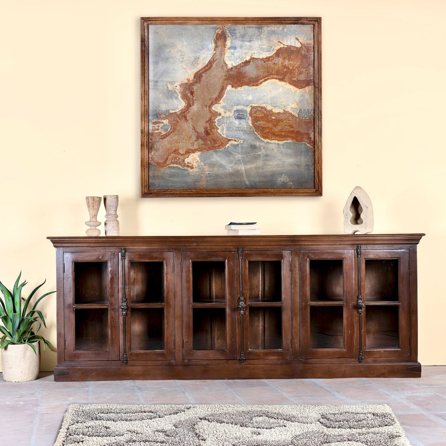 Wooden sideboard with decorative items and a large framed abstract painting in a living room setting.