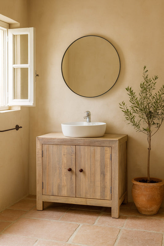 Bathroom with wooden vanity, round mirror, and potted plant.