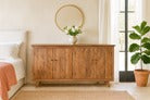 Wooden dresser in a bedroom with a mirror and plants