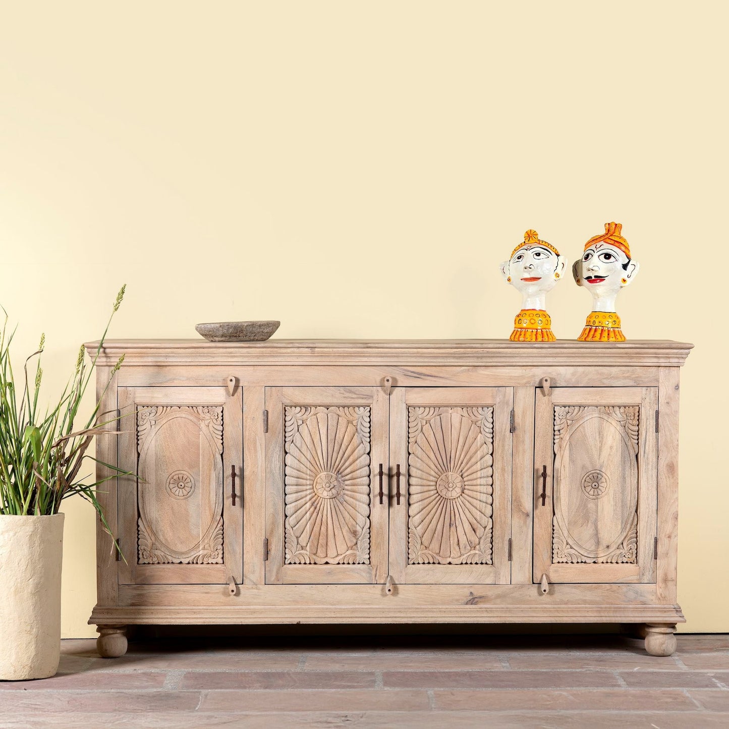 Wooden cabinet with decorative carvings on a wooden floor against a beige wall.