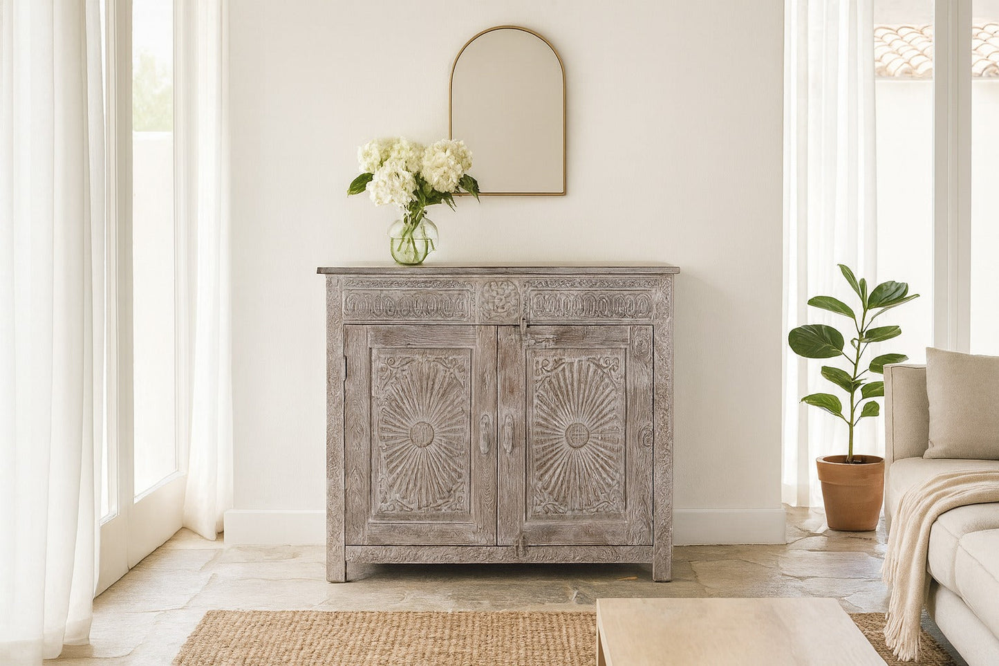Wooden cabinet with decorative sunburst pattern in a bright room with a mirror and plant.