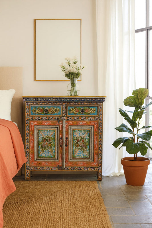 Decorative cabinet with floral patterns in a room with a plant and framed picture.
